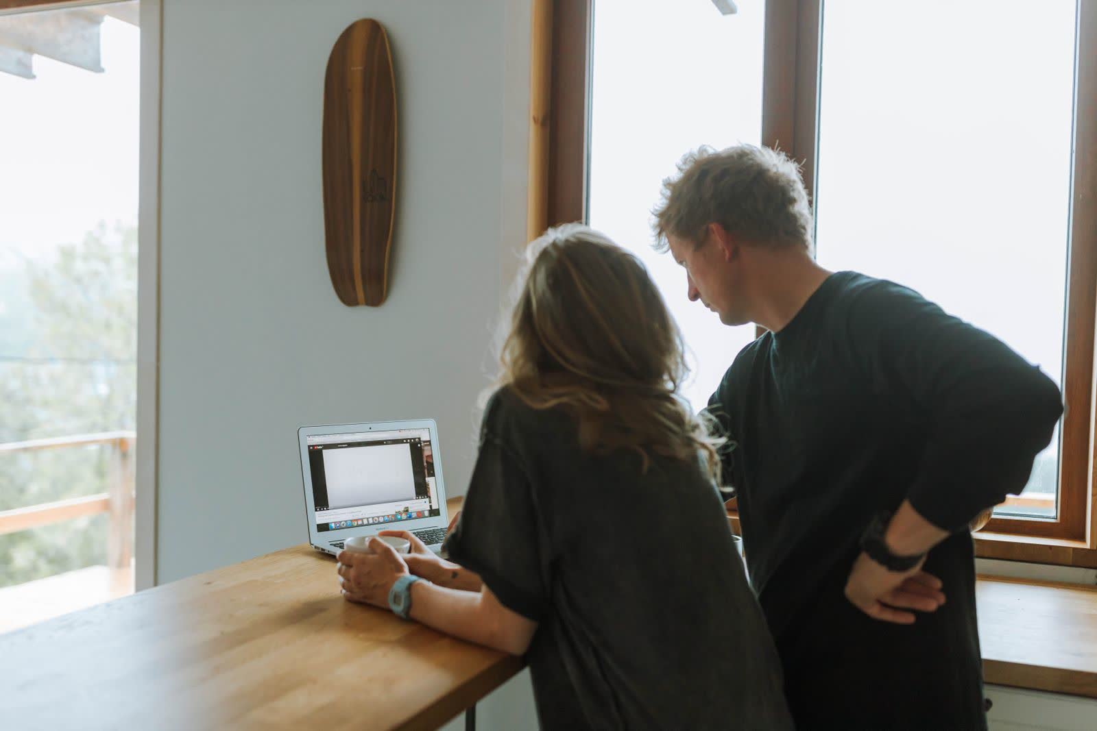 Twee ondernemers die samen aan een tafel bij het raam naar een laptop kijken